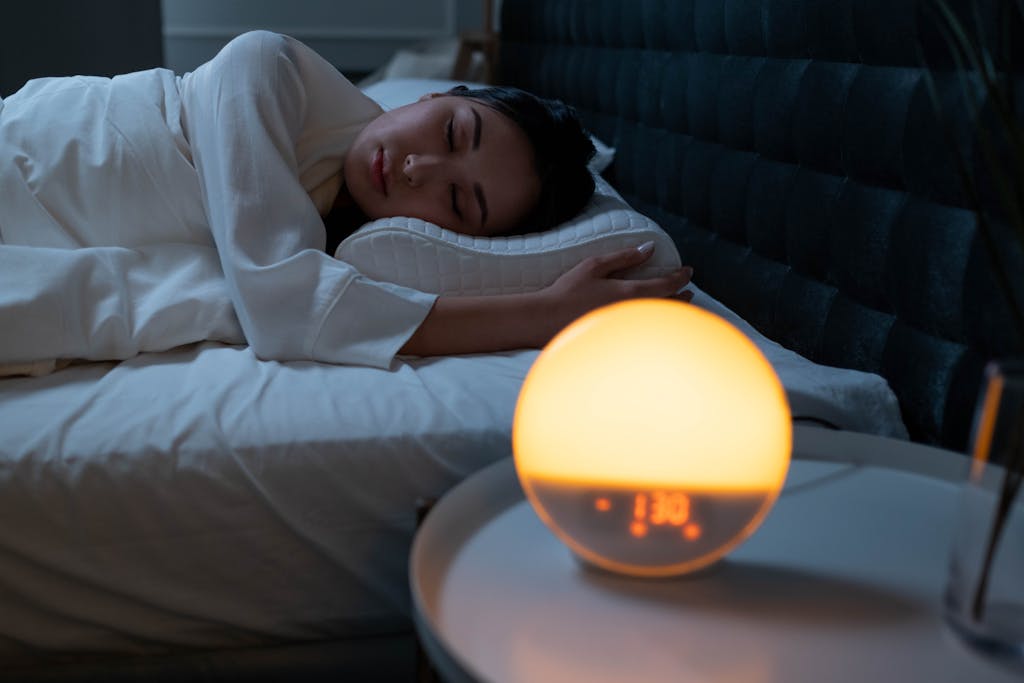 Woman sleeping peacefully in a cozy bedroom with ambient bedside light.